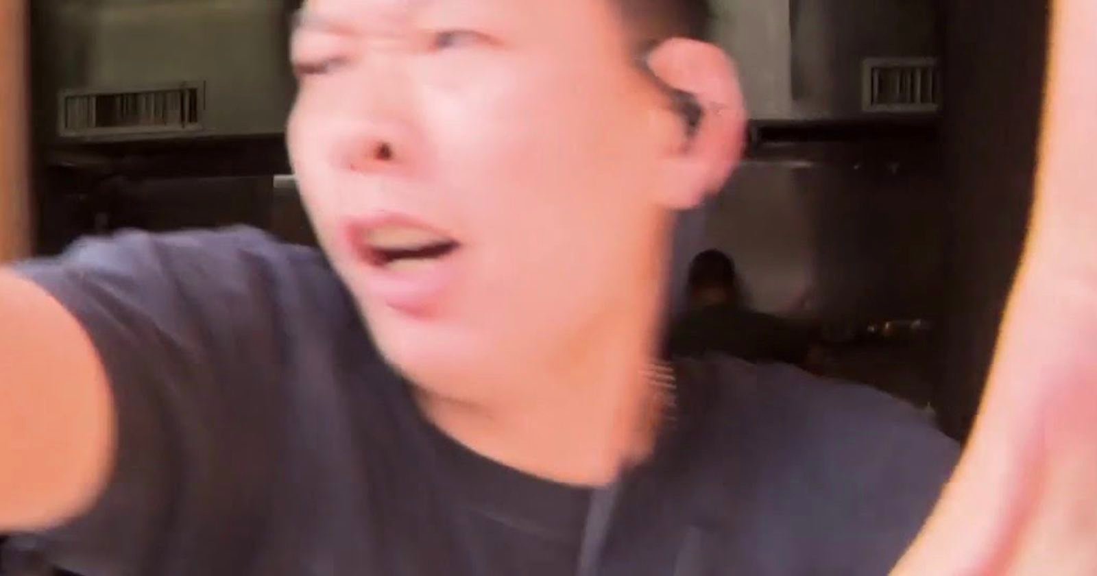 A person in a black shirt with an earpiece appears to be in motion, with a blurred, surprised expression, and their arm extended toward the camera. The background shows an indoor setting with metal surfaces. A person in a black shirt with an earpiece appears to be in motion, with a blurred, surprised expression, and their arm extended toward the camera. The background shows an indoor setting with metal surfaces.