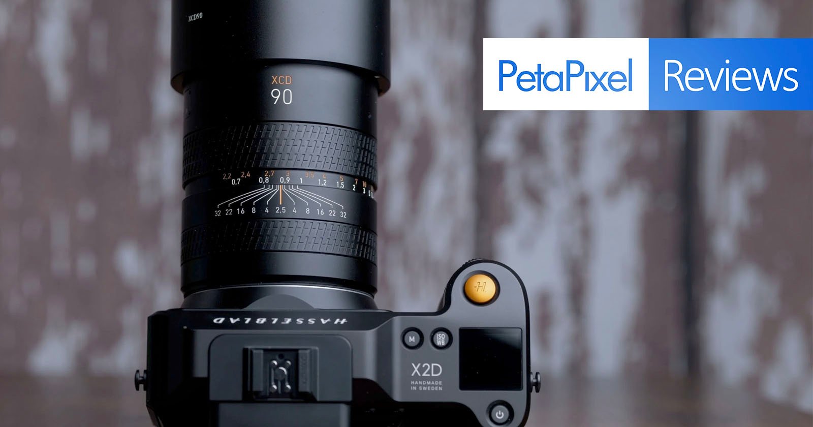 A hasselblad x2d camera with a large lens attached, positioned on a wooden surface with a blurred background, showcasing the petapixel reviews logo overlaid on the image.