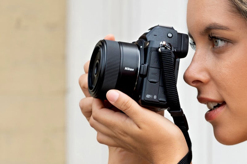 A Nikon camera and lens held up to a woman's eye