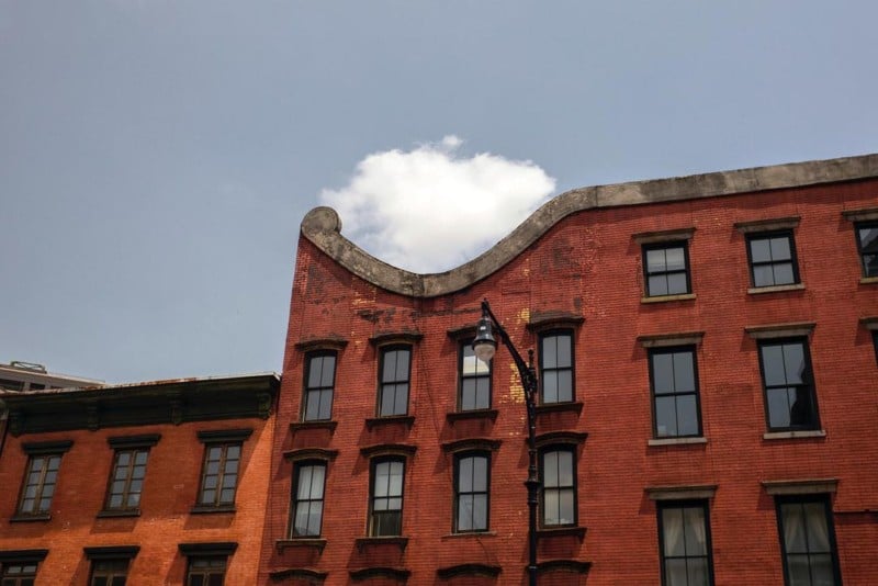A cloud framed in the curve of a tall brick building