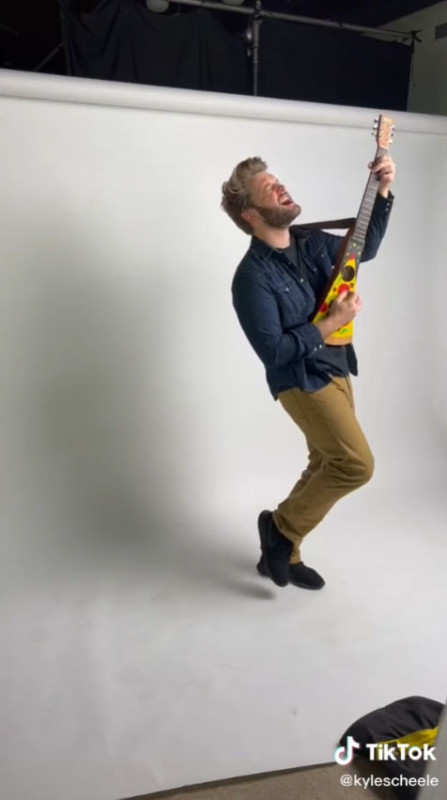 A man posing for a photo shoo with a pizza guitar A man posing for a photo shoo with a pizza guitar