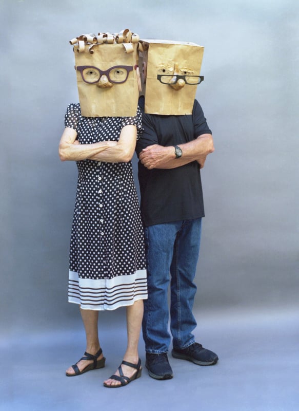 Two people wearing paper bags with faces on their heads