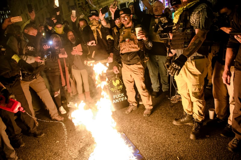 A ‘Proud Boy’ adds fuel to a ‘Black Lives Matter’ flag on fire as leader Enrique Tarrio and other members gather in the streets following the ‘Million MAGA March’ on Dec. 12, 2020, in Washington, D.C.