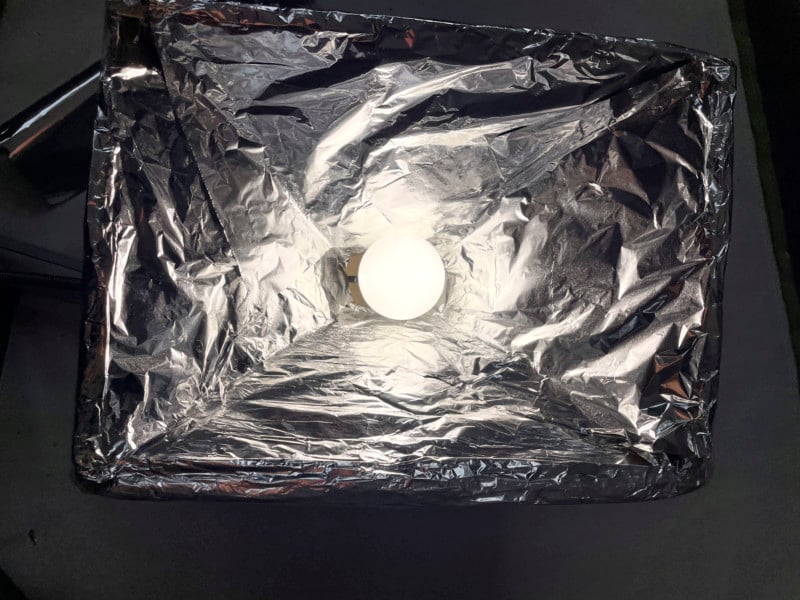 A foil-lined DIY softbox with a light bulb inside A foil-lined DIY softbox with a light bulb inside