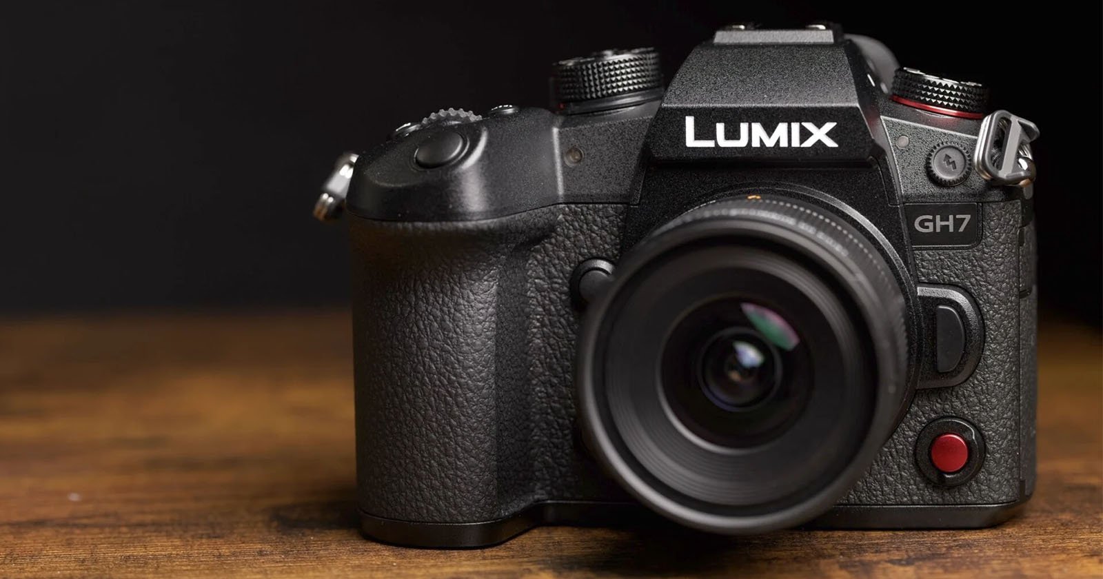 A black Panasonic LUMIX GH7 camera with a wide-angle lens is placed on a wooden surface, against a dark background. The camera has a textured grip, various buttons, and a large viewfinder. The brand name LUMIX is clearly visible above the lens. A black Panasonic LUMIX GH7 camera with a wide-angle lens is placed on a wooden surface, against a dark background. The camera has a textured grip, various buttons, and a large viewfinder. The brand name LUMIX is clearly visible above the lens.