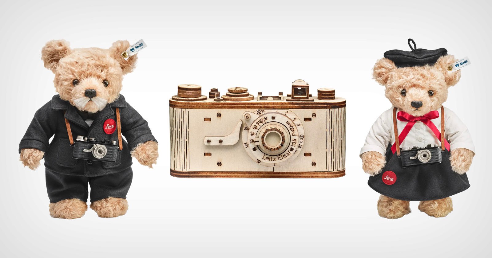 Two teddy bears dressed as photographers stand beside a vintage camera model. One bear wears a black suit and the other wears a black beret and white shirt. Each holds a miniature camera around their neck. The camera model is wooden with detailed features. Two teddy bears dressed as photographers stand beside a vintage camera model. One bear wears a black suit and the other wears a black beret and white shirt. Each holds a miniature camera around their neck. The camera model is wooden with detailed features.
