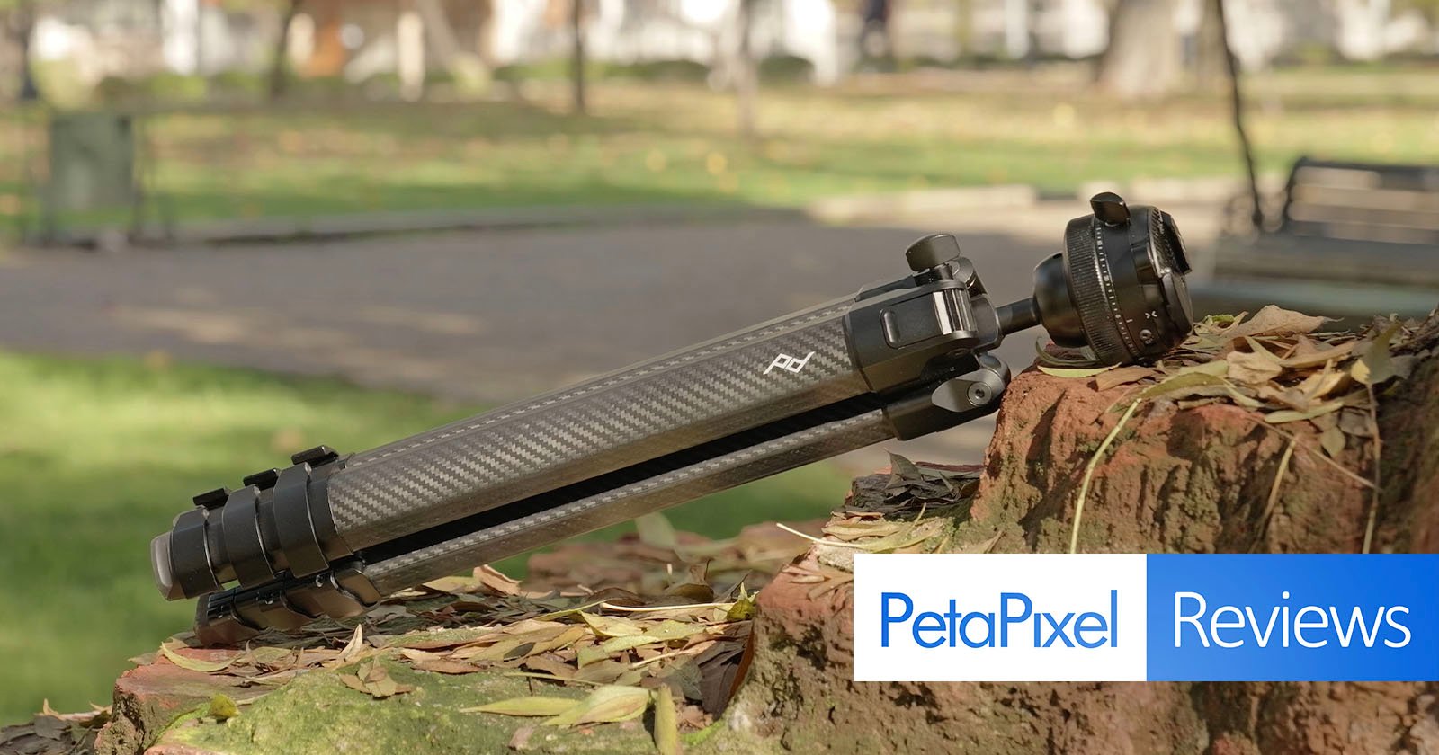 A black camera tripod rests on a mossy brick wall in a park, with fallen leaves around. The Petapixel Reviews logo is overlaid in the bottom right corner of the image. A black camera tripod rests on a mossy brick wall in a park, with fallen leaves around. The Petapixel Reviews logo is overlaid in the bottom right corner of the image.