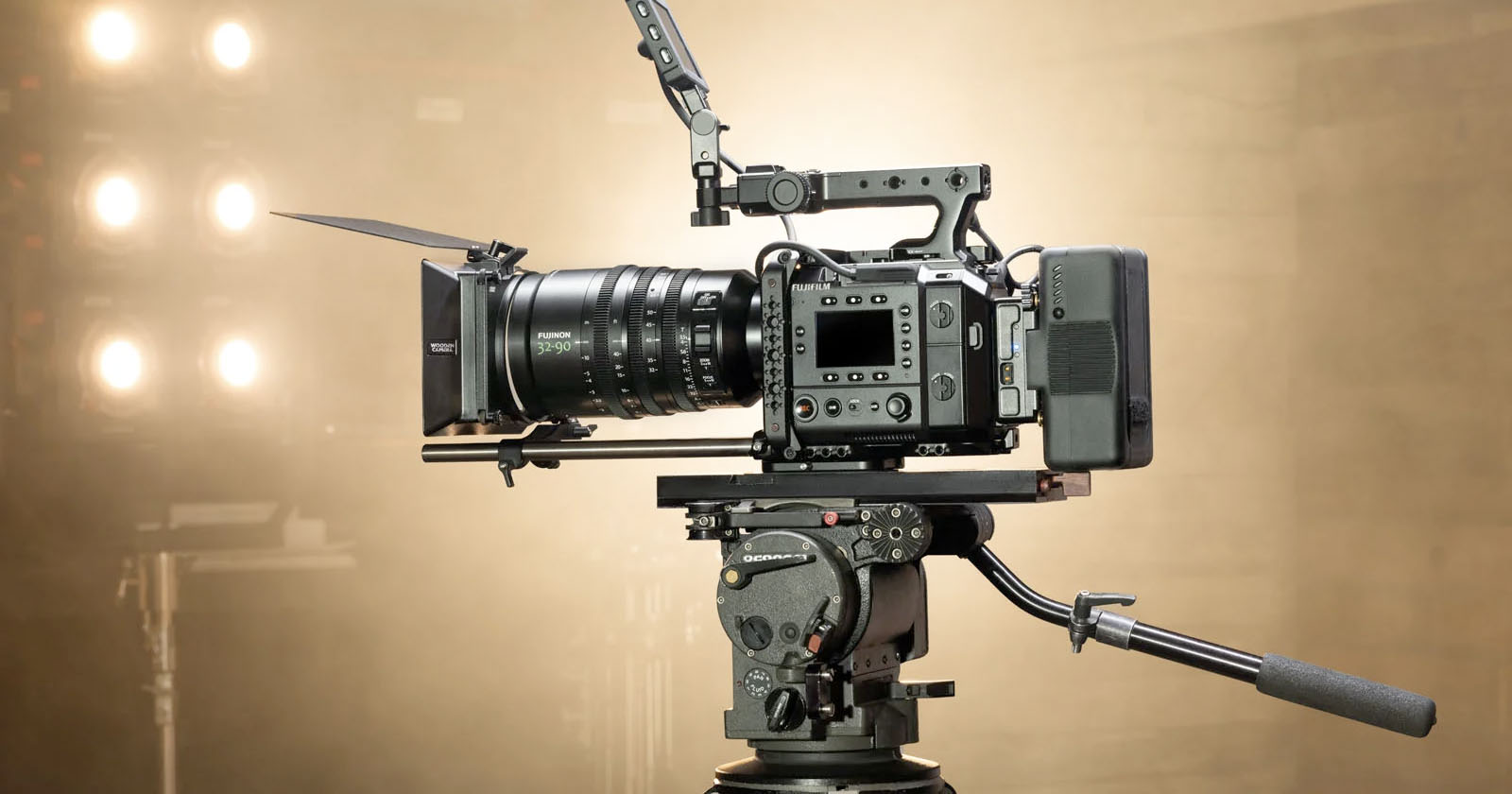A professional video camera with a large lens and matte box mounted on a tripod, set up in a studio with bright lights in the background. A professional video camera with a large lens and matte box mounted on a tripod, set up in a studio with bright lights in the background.