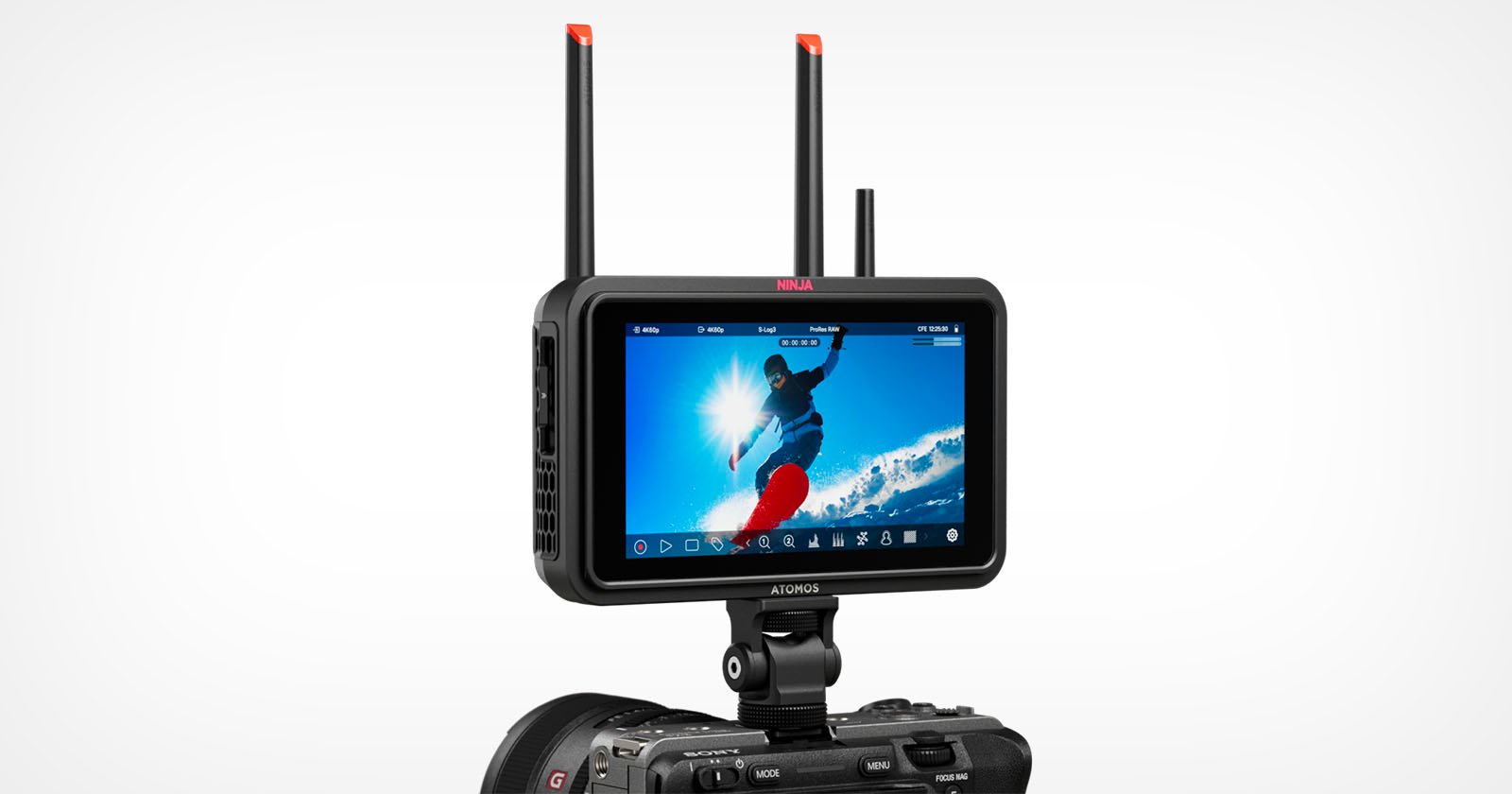 A digital camera with a mounted Atomos Ninja video monitor displaying a snowboarder mid-air against a bright blue sky, with two antennas extending from the monitor for wireless connectivity. A digital camera with a mounted Atomos Ninja video monitor displaying a snowboarder mid-air against a bright blue sky, with two antennas extending from the monitor for wireless connectivity.