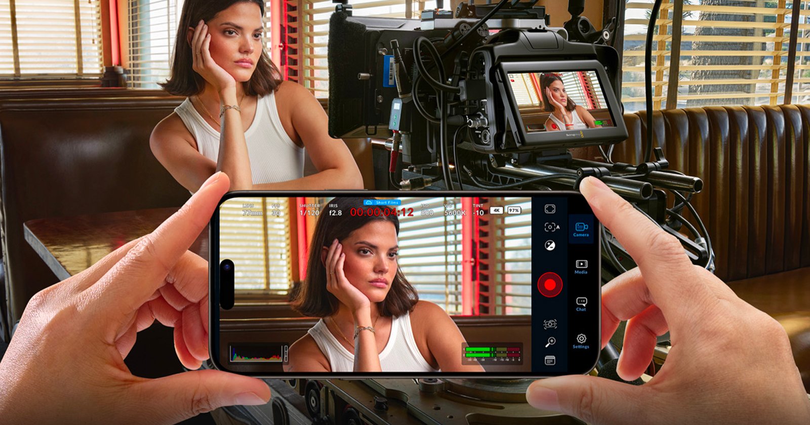 A woman sits in a diner booth, resting her head on her hand, as she is filmed by a camera. A person holds up a smartphone displaying a live recording of the woman in the foreground. A woman sits in a diner booth, resting her head on her hand, as she is filmed by a camera. A person holds up a smartphone displaying a live recording of the woman in the foreground.