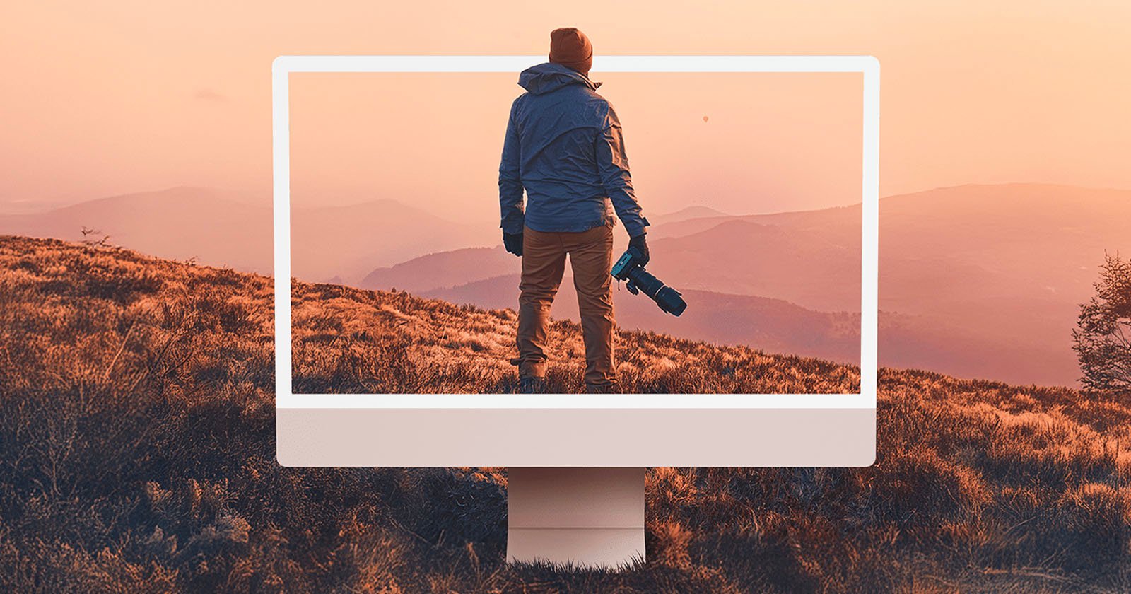 A person holding a camera stands on a grassy hill at sunset, with an oversized computer monitor frame highlighting them and the mountain landscape in the background. A person holding a camera stands on a grassy hill at sunset, with an oversized computer monitor frame highlighting them and the mountain landscape in the background.