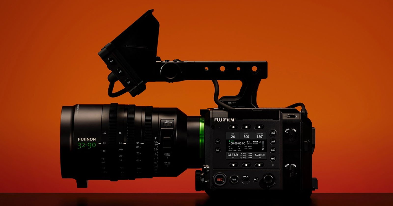 A professional cinema camera with a large Fujinon lens is displayed in profile against a vibrant orange background. The camera features various control buttons and a top handle. A professional cinema camera with a large Fujinon lens is displayed in profile against a vibrant orange background. The camera features various control buttons and a top handle.